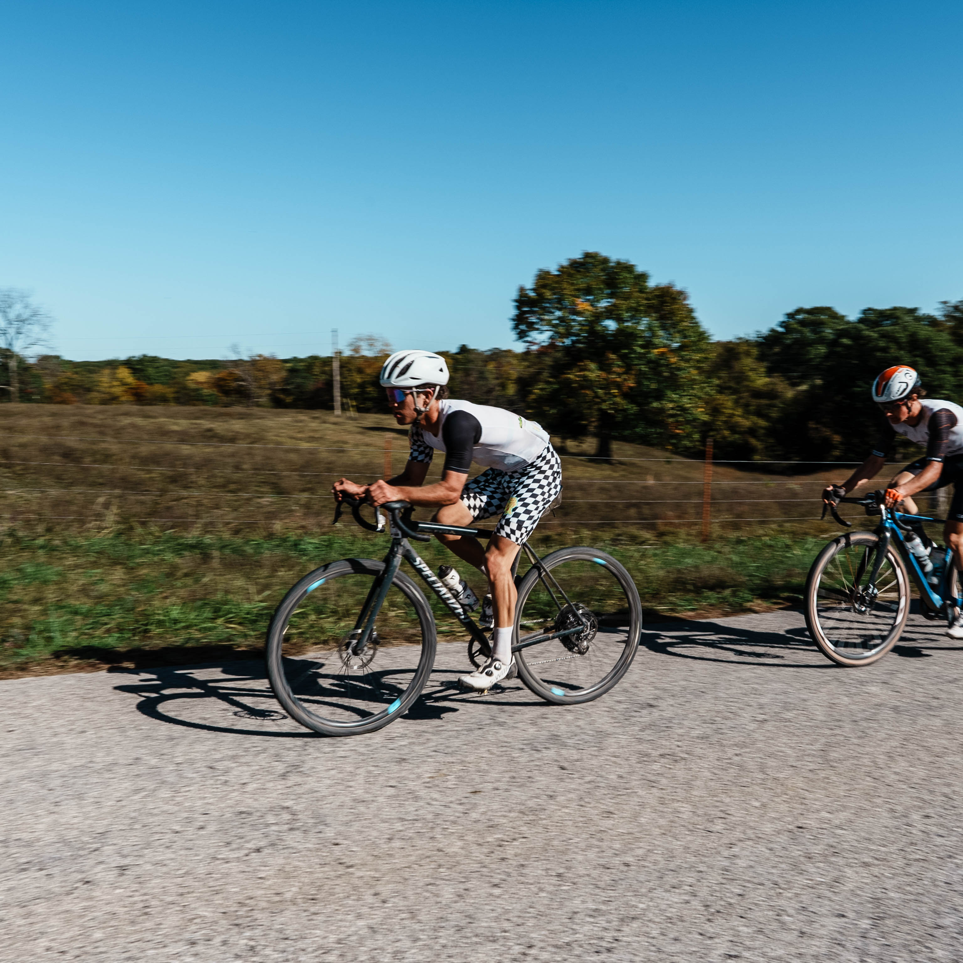 Cyclist on paved road with trees in background