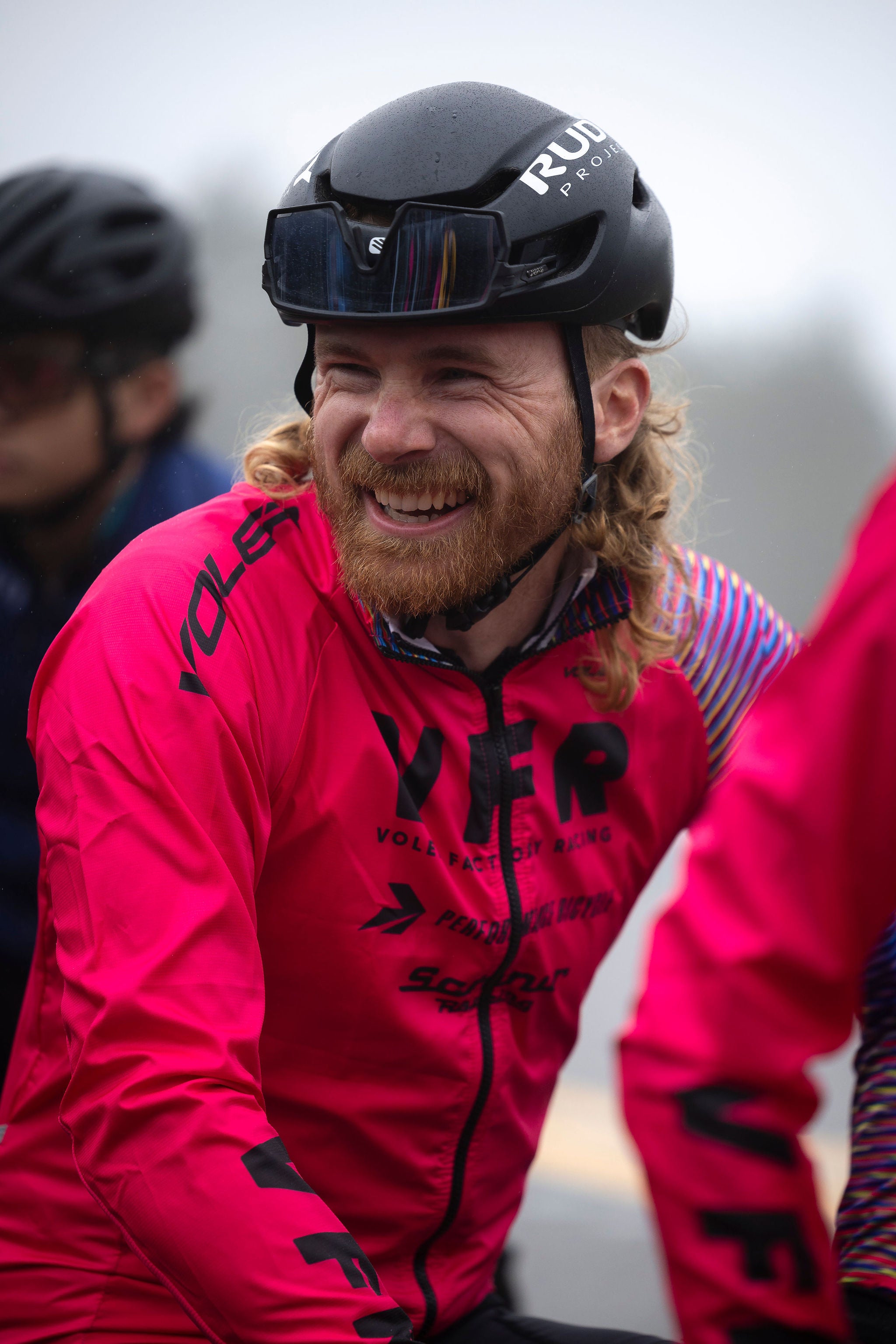 A smiling rider in a bright pink Voler Factory Racing jersey