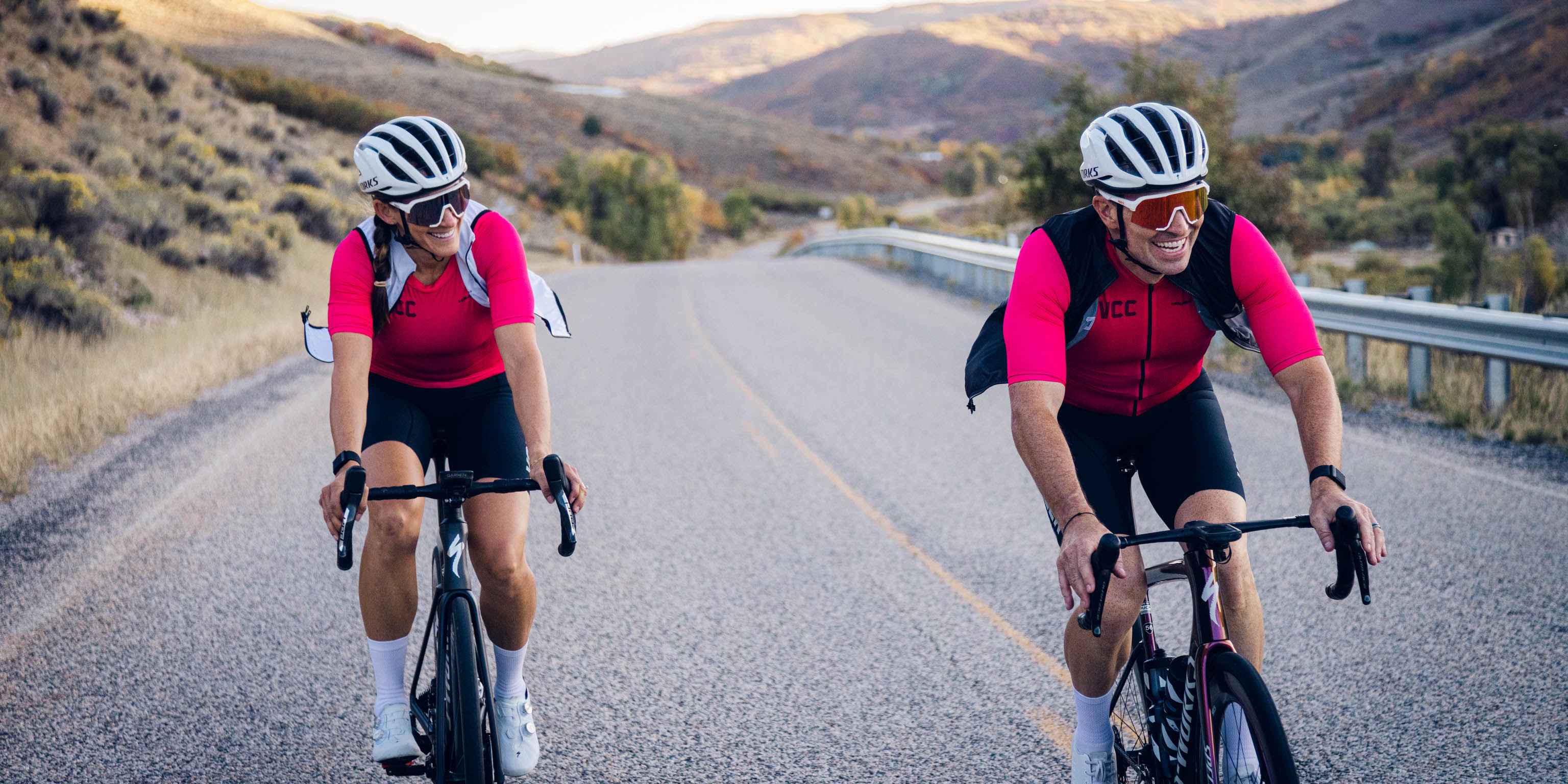 man and woman cycling on road with big smiles