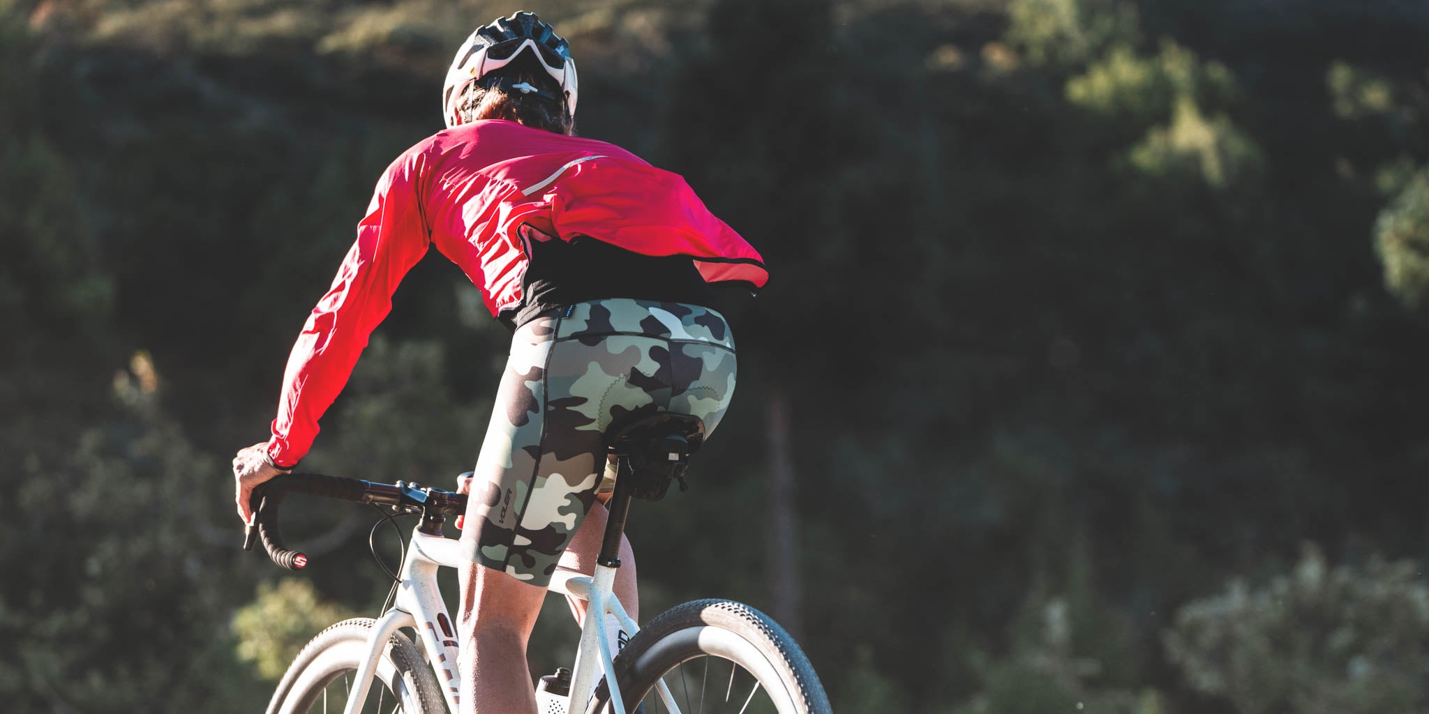 Person riding a bicycle with a helmet and red jacket in a natural setting
