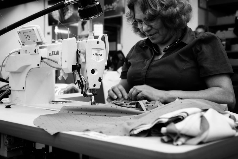 A member of the Voler team guiding patterned fabric at a sewing machine.